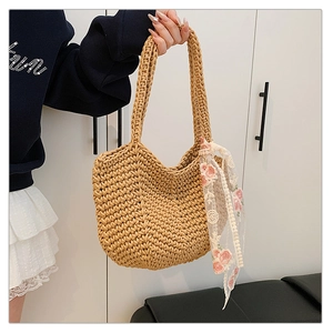 Detail of woven straw tote bag featuring a floral lace scarf tied on the handle