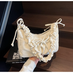 Detail of white pleated PU leather shoulder bag with decorative bows and cloud-like handle