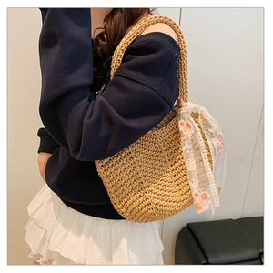 Detail view of woven straw tote bag with white lace flower embroidery for summer holidays
