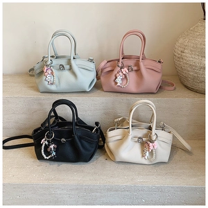 Detail view of four minimalist pleated handbags in blue, pink, black, and beige with charms