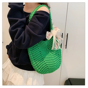 Detailed close-up of green woven tote bag with lace bow and floral embroidery decoration