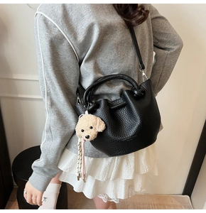 Détail du sac seau noir en cuir avec un charmant pendentif d'ours en peluche
