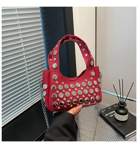 Dettaglio della borsa a secchiello in pelle rossa con borchie e tracolla a catena