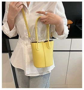 Detail of yellow lychee textured bucket bag with handles and slim crossbody strap