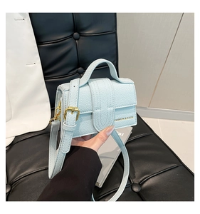Close-up detail of mini light blue pebbled leather square bag with elegant gold lettering