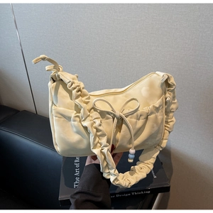 Detailed view of cream ruffled underarm bag with bow decoration and pleated shoulder strap