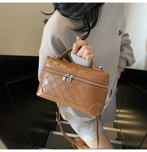 Close-up of brown quilted leather texture and silver zipper on women's box bag