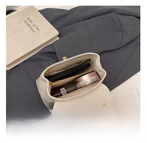 Vista interna della borsa in pelle crema con telefono, rossetto e vari scomparti interni