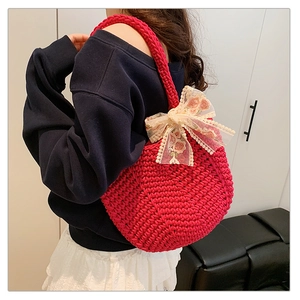 Detail of red knit round tote bag with large beige floral lace bow accessory