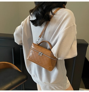 Brown box-shaped crossbody bag with quilted diamond pattern shown on a model's back