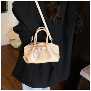 Detail of beige pleated leather bucket bag with cute charm on a black blazer outfit