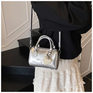 Dettaglio della borsa Boston metallizzata argento con ciondolo a cuore e perle