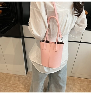 Detail view of pink litchi grain bucket bag with vertical stitching and leather handle