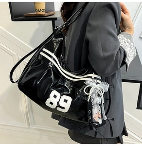 Détail d'un sac cabas en cuir verni noir avec nœud en dentelle et accessoires en perles
