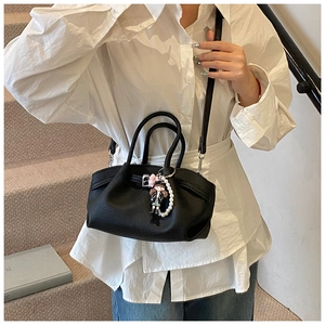 Close-up of black lychee leather bag with pearl charms on model in casual wear