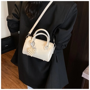 Borsa Boston color panna con ciondolo a cuore di perle mostrata su un blazer nero