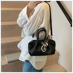 Close-up of black pleated tote bag with pearl charm and adjustable shoulder strap