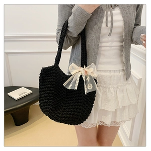 Detail of hand-woven black tote bag featuring a large white lace bow with embroidery