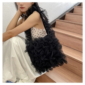 Detailed close-up of tiered black lace ruffles and pleated mesh texture on the tote bag