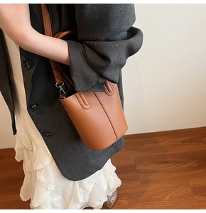 Detailed view of brown litchi grain leather bucket bag with silver metal buckles