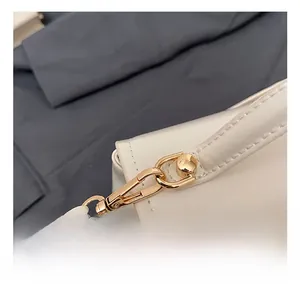 Dettaglio dei ganci in metallo dorato su una borsa a mano in pelle bianca da donna
