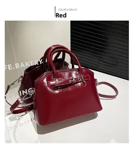 Close-up of red patent leather shell bag with silver hardware and detachable strap