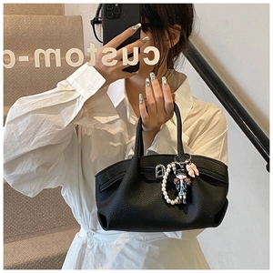 Detail of black lychee grain leather handbag with pearl chain and cartoon doll charm