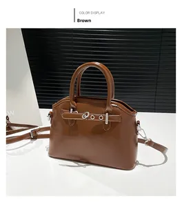 Detail view of brown oil wax leather handbag with silver hardware and shoulder strap