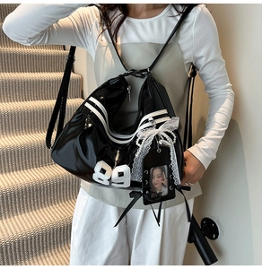 Détail du sac noir brillant avec broderie 89 et accessoire nœud en dentelle et perle
