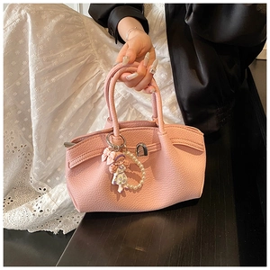 Close-up of pink pleated leather bag with pearl girl doll charm and metal hardware