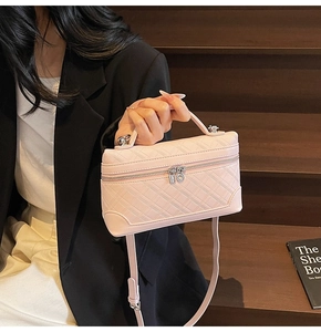 Pink quilted leather box bag with silver zippers shown in a stylish seating pose