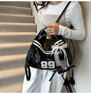 Détail du sac hobo en cuir verni noir avec imprimé 89 et breloque en dentelle et perles