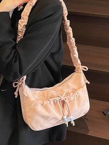 Pink satin shoulder bag with ruffled strap and bow detail worn with black blazer