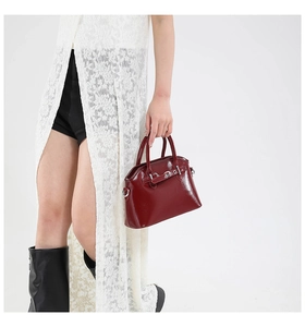 Close-up of wine red oil wax leather handbag with glossy finish and metal buckles