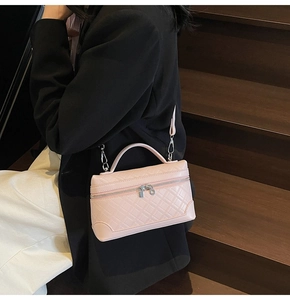 Pink quilted leather crossbody bag worn by a model against a wooden staircase background