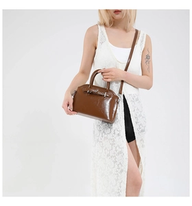 Detail of a deep brown oil wax leather handbag with silver hardware and shoulder strap