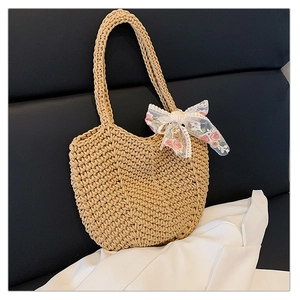 Close-up of woven straw tote bag featuring detailed lace bow and pink floral embroidery