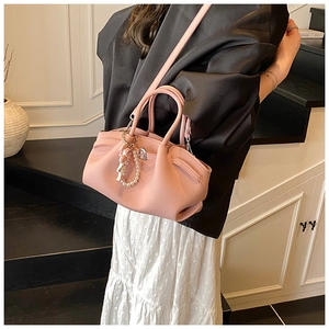 Detail of pink pleated handbag with lychee leather texture and pearl doll accessory