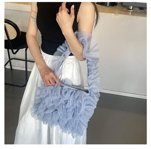 Detail showing the pleated mesh ruffles and soft texture of the blue tote bag