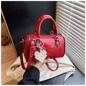 Dettaglio borsa Boston rossa con goffratura AJAR & DDW e ciondolo cuore di perle