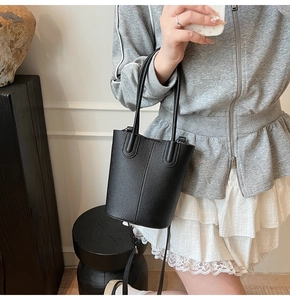 Detail of black lychee textured leather bucket bag worn with a casual summer outfit