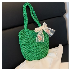Close-up of green crochet tote bag featuring intricate knit texture and lace bow detail