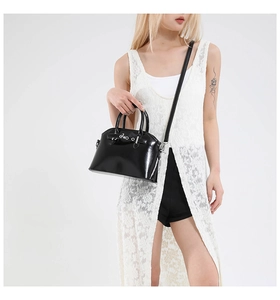 Polished black dome bag featuring shiny oil wax leather and silver hardware accents