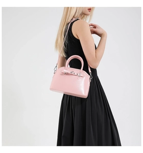 Detailed view of pink glossy shell bag with metal hardware and thin shoulder strap