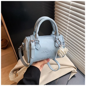 Dettaglio della borsa Boston azzurra con logo goffrato e ciondolo a cuore di perle
