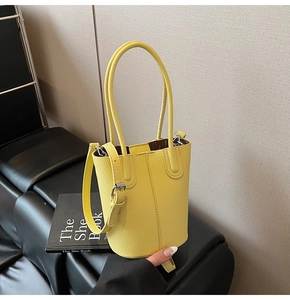 Detail view of yellow litchi pattern bucket bag showing stitching and side strap