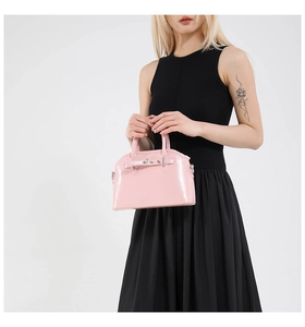 Close-up of pink patent leather shell bag with silver buckles and polished finish