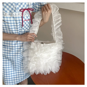 Detail view of the metal magnetic closure and ruffled white lace fabric of the tote bag