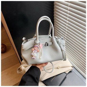 Close-up of gray-blue pebble leather bag with pearl chain and cute doll charm