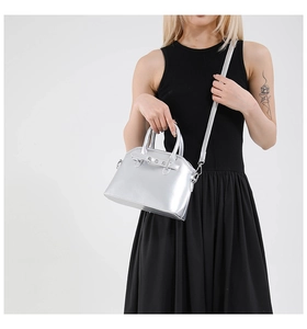 Detail view of silver metallic shell bag with rivet accents and slender shoulder strap
